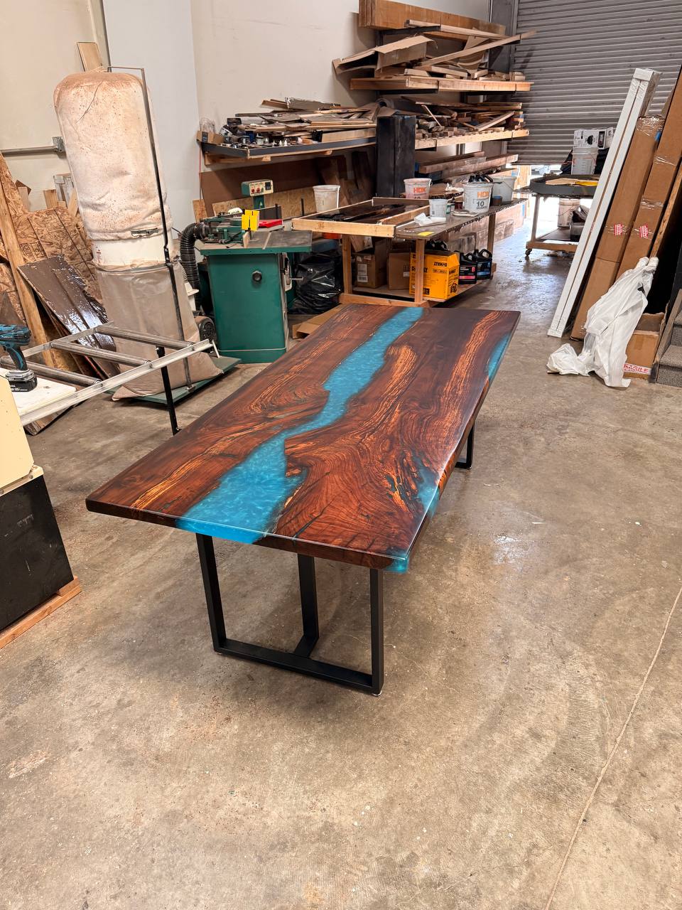 Seven-foot walnut and blue epoxy river table on black metal legs in the FamilyWood workshop