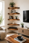 A styled living room corner with five rustic floating wooden shelves mounted on a white wall. The shelves are decorated with potted green plants, books, a small picture frame, and candles.
