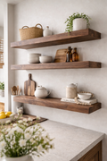 Three substantial walnut floating shelves above a light kitchen counter